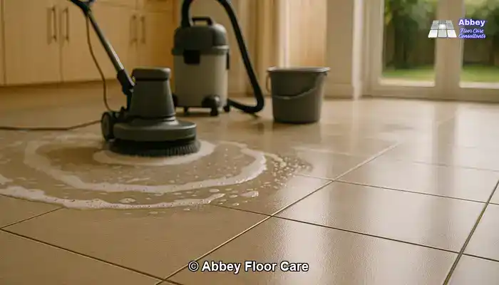 Tiled floor in a UK home during professional cleaning with a rotary machine and wet vacuum, showing a clear contrast between cleaned and uncleaned areas.